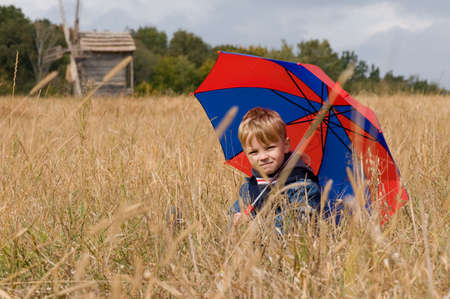 Little boy with his umbrella in autumn dayの写真素材