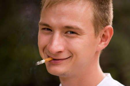 A young man smoking cigarette, focus is set at his faceの写真素材