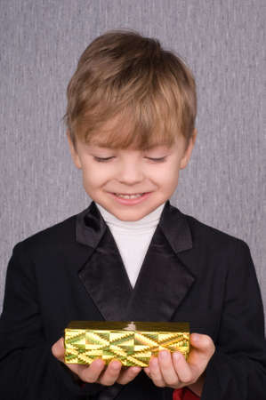 Beautiful little boy with golden gift boxの写真素材