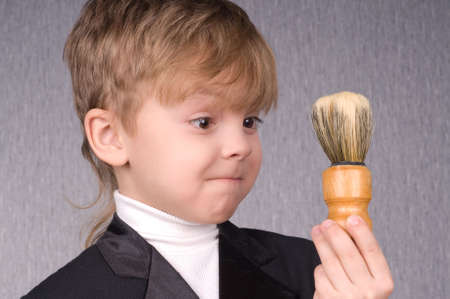 Beautiful little boy with golden gift box and shaving brushの写真素材