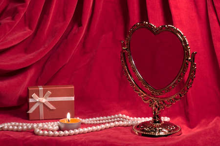 Mirror in the form of heart, pearly necklace, light,  red gift box. Valentine's day card.の写真素材