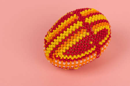 An easter egg is decorated a beads on a pink backgroundの写真素材