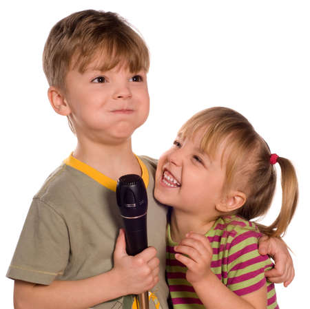 Child singing with a microphone. Funny little girl and boy isolated on white background. Beautiful caucasian model.の写真素材