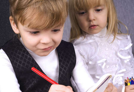 Beautiful little girl and boy is drawing with pencils on paperの写真素材