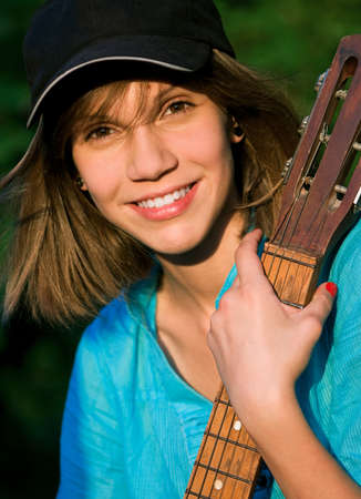 Beautiful teenage girl with guitar in the green parkの写真素材