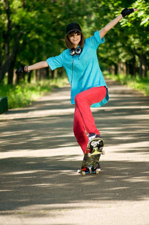 Beautiful teenage girl with skateboard in the green parkの写真素材