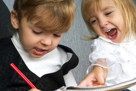 Beautiful little girl and boy is drawing with pencils on paperの写真素材