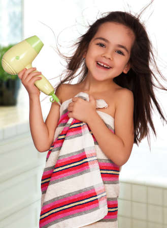 Little girl dries hair after bathing in bathroomの写真素材