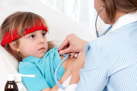 Woman doctor examines sick little beautiful girlの写真素材