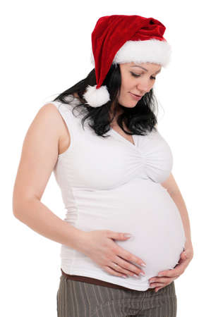 Portrait of a pregnant woman in santa hat over white background. Third trimester.の写真素材