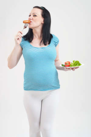 Pregnant woman with a plateful of salad on a grey backgroundの写真素材