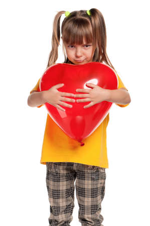 Portrait of little girl with red heart balloon over white backgroundの写真素材