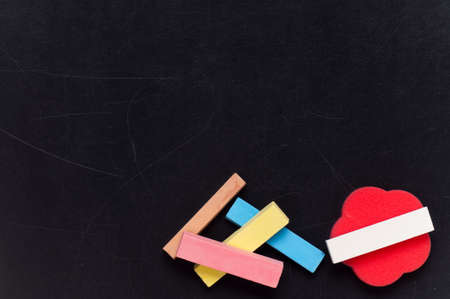 Empty blank black chalkboard with red sponge and colorful chalkの写真素材