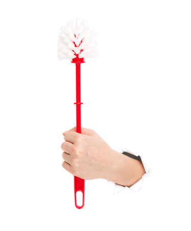 Woman hand with plastic red toilet brush through a hole in paper isolated on white backgroundの写真素材
