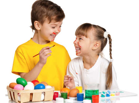 Two children painting Easter eggs isolated on white backgroundの写真素材