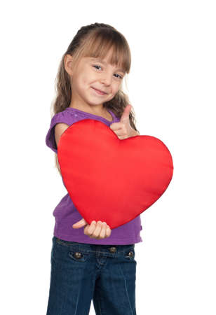 Portrait of little girl holding red heart and giving you thumb up over white backgroundの写真素材