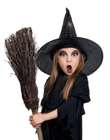 Portrait of little girl in black hat and black clothing with broom on white backgroundの写真素材