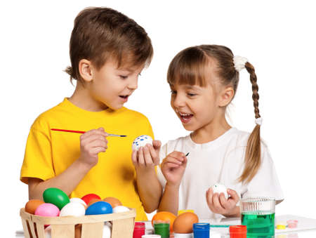 Two children painting Easter eggs isolated on white backgroundの写真素材