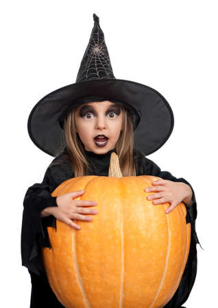 Portrait of little girl in black hat and black clothing with pumpkin on white backgroundの写真素材