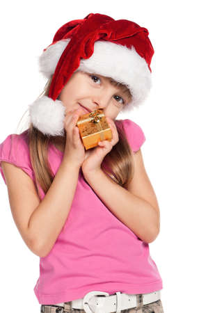 Portrait of happy little girl in santa hat with gift box over white backgroundの写真素材