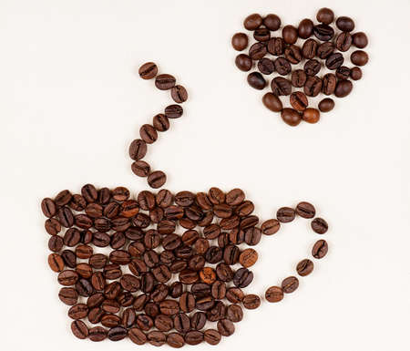 Cup made of coffee beans with heart on the light canvasの写真素材