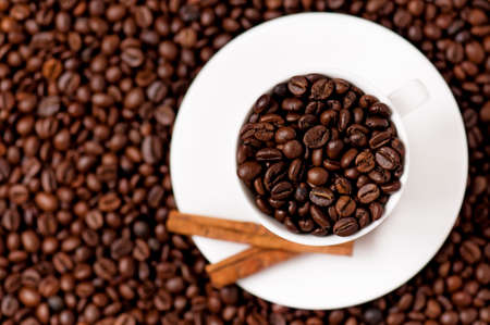 White coffee cup with spices on coffee beans - top view - focus on cupの写真素材
