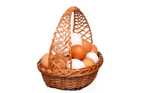 Brown and white eggs in the wicker basket over white backgroundの写真素材