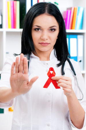 Female doctor holding a red ribbon as a symbol of AIDS