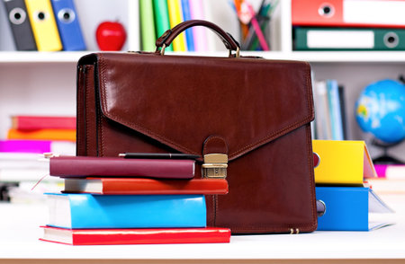 Brown leather briefcase and books on table at office