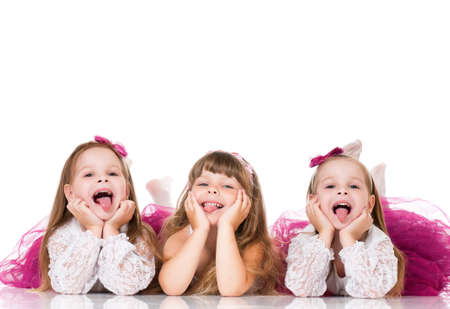 Group of adorable little girls having fun lying on floor, isolated on white backgroundの写真素材