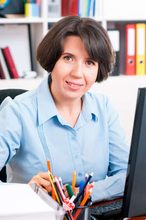 Beautiful business woman at workplace looking at cameraの写真素材