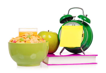 Big green alarm clock with book and breakfast, isolated on white backgroundの写真素材