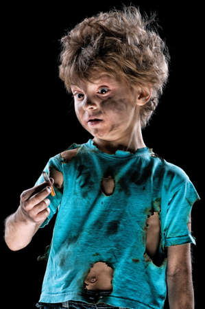 Portrait of burnt little boy with cigarette butt, over black backgroundの写真素材