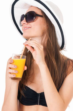 Pretty girl posing in bikini, summer hat and sunglasses, with orange juice, isolated on white backgroundの写真素材
