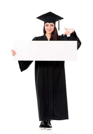 Beautiful graduate girl student in mantle showing blank placard board, isolated on white backgroundの写真素材