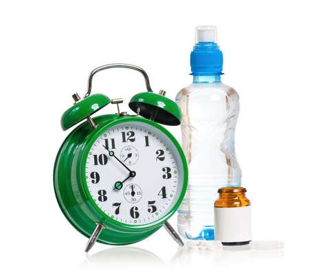 Big green alarm clock with pills, isolated on white backgroundの写真素材