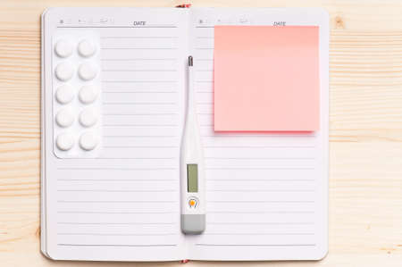Blank notepad with thermometer on the wooden table. View from aboveの写真素材