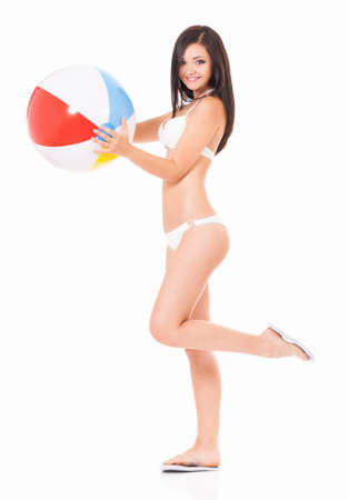 Full length portrait of happy young woman in a white bikini  with beach ball, isolated on white backgroundの写真素材