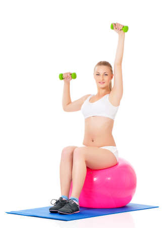Young woman in fitness wear exercising with fitness-ball and dumbbells, isolated on white backgroundの写真素材