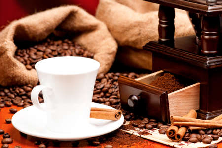 Coffee grinder and cup of coffee with spices on dark red backgroundの写真素材