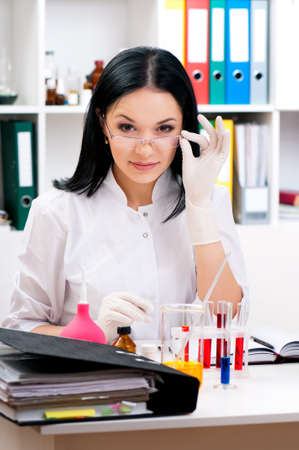 Smiling medical doctor woman analyzing a blood sample at workplaceの写真素材