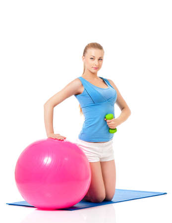 Young woman in fitness wear exercising with fitness-ball and dumbbells, isolated on white backgroundの写真素材