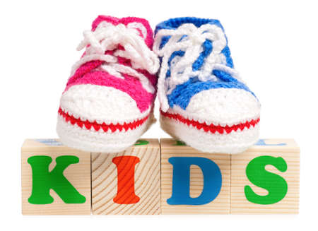 Kids word formed by wood alphabet blocks with booties for baby, isolated on white backgroundの写真素材