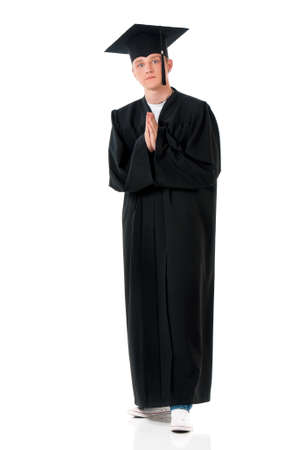Handsome graduate guy student in mantle - hands folded in prayer, isolated on white backgroundの写真素材