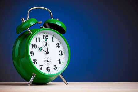 Big green alarm clock on dark blue backgroundの写真素材