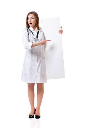 Happy young female doctor with stethoscope showing blank placard board, isolated on white backgroundの写真素材