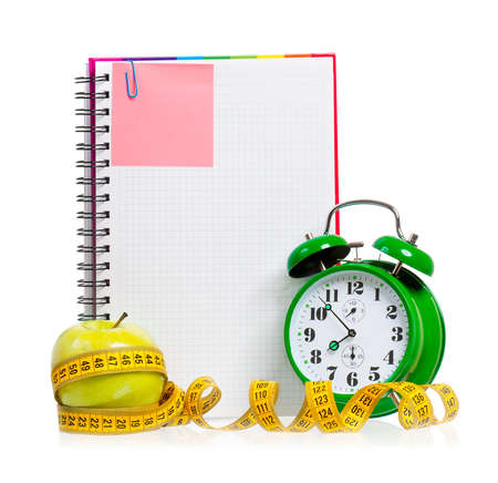 Concept of diet - alarm clock, apple, measuring tape and  blank notebook,  isolated on white backgroundの写真素材