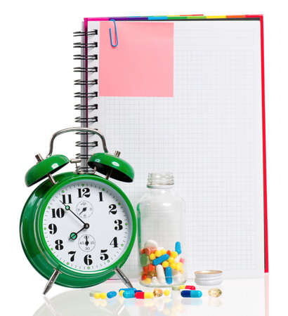 Medical concept - green alarm clock with pills, water and blank notebook,  isolated on white backgroundの写真素材