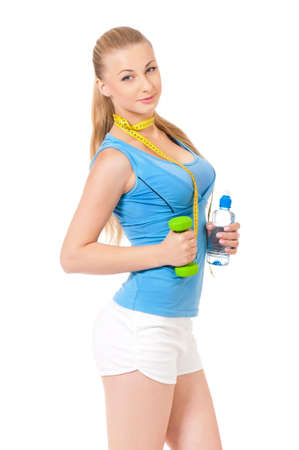 Woman exercising with dumbbell, bottle of water and measuring tape, portrait isolated over white backgroundの写真素材