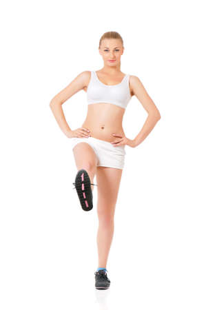 Fitness woman doing stretching exercise, full length portrait isolated over white backgroundの写真素材